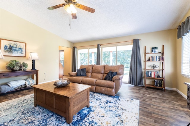 living room featuring ceiling fan, a wealth of natural light, dark hardwood / wood-style floors, and a textured ceiling