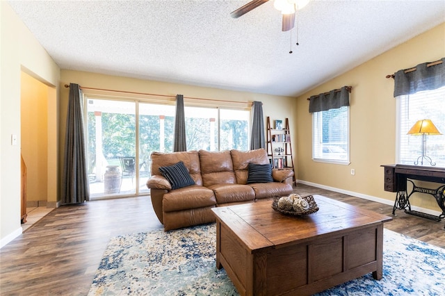 living room with a textured ceiling, hardwood / wood-style floors, ceiling fan, and vaulted ceiling