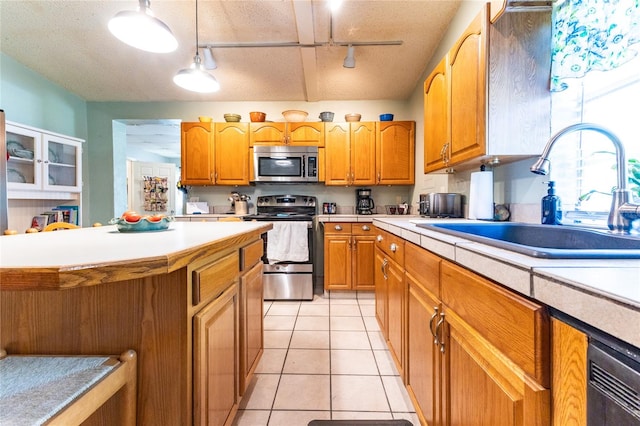 kitchen with stainless steel appliances, track lighting, hanging light fixtures, a textured ceiling, and sink