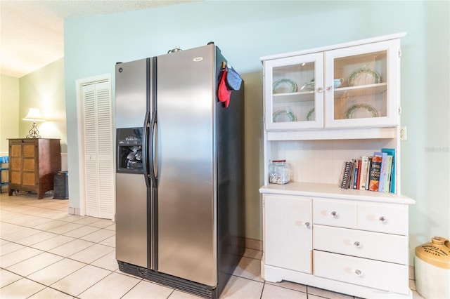 kitchen featuring white cabinets, a textured ceiling, light tile patterned floors, and stainless steel fridge with ice dispenser