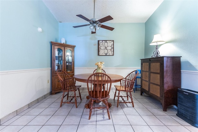 dining area with a textured ceiling, ceiling fan, vaulted ceiling, and light tile patterned floors