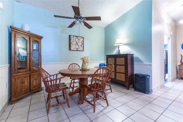 dining area featuring ceiling fan, a textured ceiling, vaulted ceiling, and light tile patterned floors