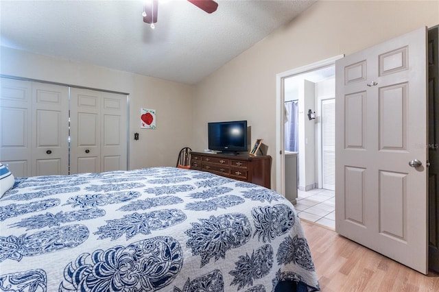 bedroom with light hardwood / wood-style floors, vaulted ceiling, a textured ceiling, ceiling fan, and a closet