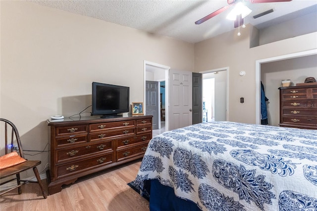 bedroom with a textured ceiling, light hardwood / wood-style floors, and ceiling fan