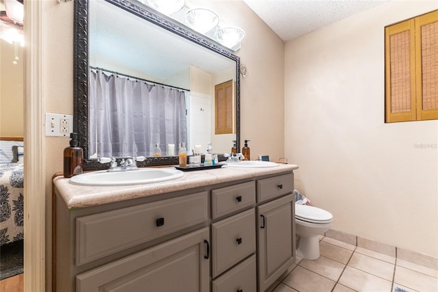 bathroom featuring toilet, vanity, a textured ceiling, and tile patterned flooring