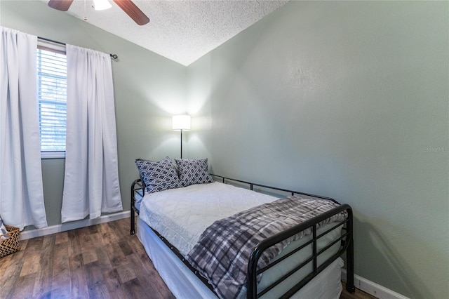 bedroom with vaulted ceiling, ceiling fan, a textured ceiling, and dark hardwood / wood-style flooring