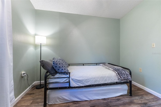 bedroom with a textured ceiling and dark hardwood / wood-style floors