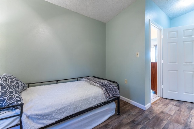 bedroom featuring lofted ceiling, hardwood / wood-style floors, and a textured ceiling