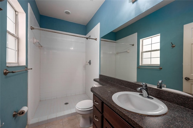 bathroom featuring tile patterned floors, toilet, vanity, and tiled shower