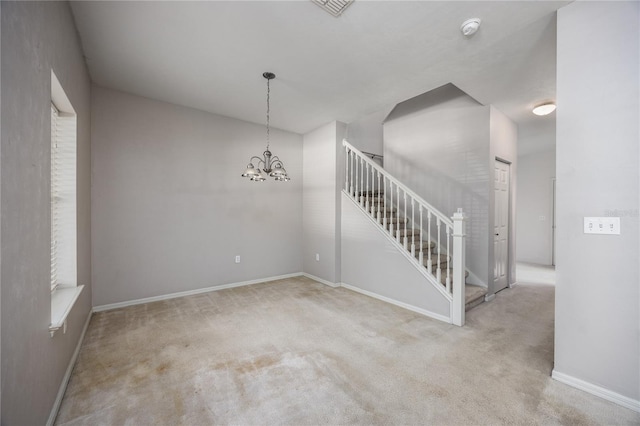 carpeted spare room with a notable chandelier