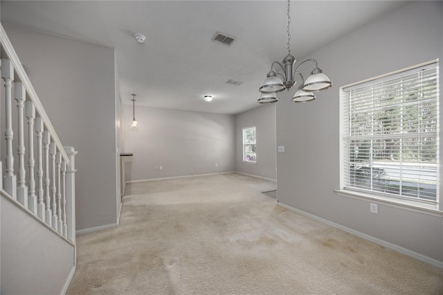 carpeted spare room featuring an inviting chandelier