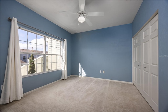 unfurnished bedroom featuring ceiling fan, a closet, and light carpet