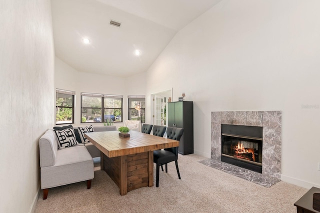 carpeted dining area featuring high vaulted ceiling