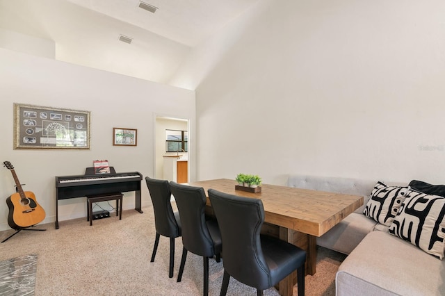 carpeted dining area with high vaulted ceiling