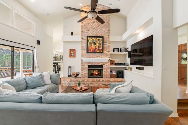 living room featuring a fireplace, hardwood / wood-style floors, high vaulted ceiling, and ceiling fan