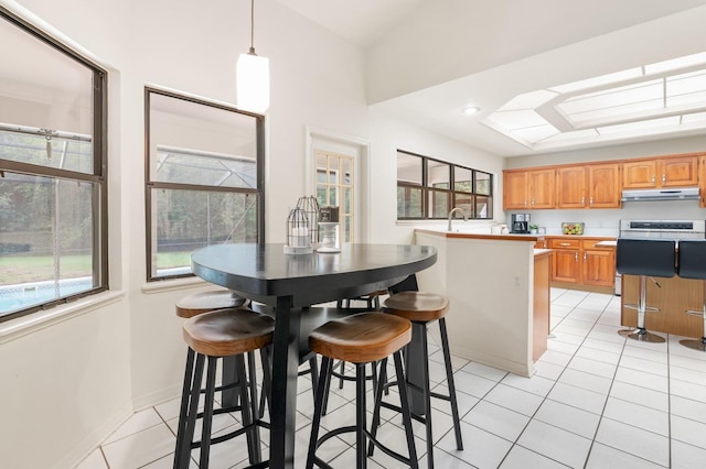 kitchen with a center island, sink, a kitchen breakfast bar, decorative light fixtures, and light tile patterned floors