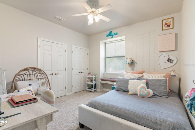 bedroom with light carpet, two closets, and ceiling fan