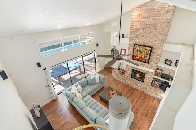 living room featuring ceiling fan, a fireplace, high vaulted ceiling, and hardwood / wood-style flooring