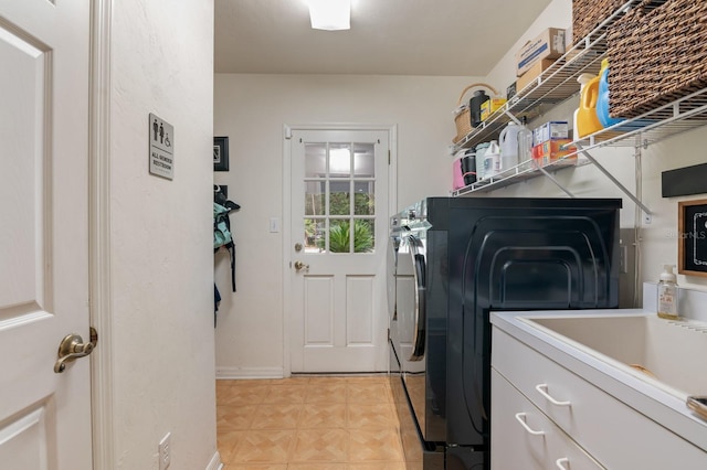 clothes washing area with washer and clothes dryer and sink