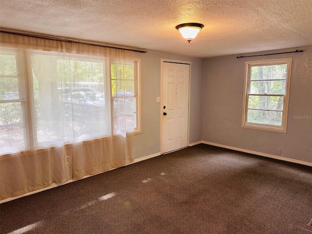 interior space with dark colored carpet and a textured ceiling