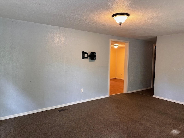 unfurnished room with dark colored carpet and a textured ceiling