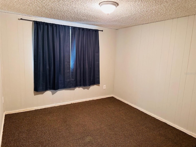 carpeted empty room with wood walls and a textured ceiling