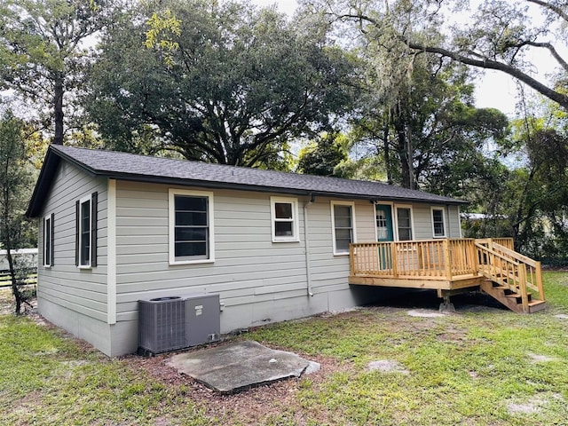 rear view of house featuring a wooden deck, cooling unit, and a lawn