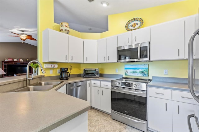 kitchen featuring vaulted ceiling, stainless steel appliances, ceiling fan, sink, and white cabinetry