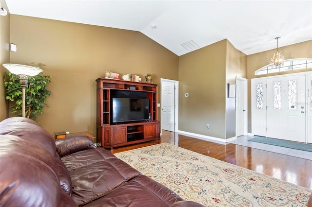 living room with lofted ceiling, an inviting chandelier, and dark wood-type flooring