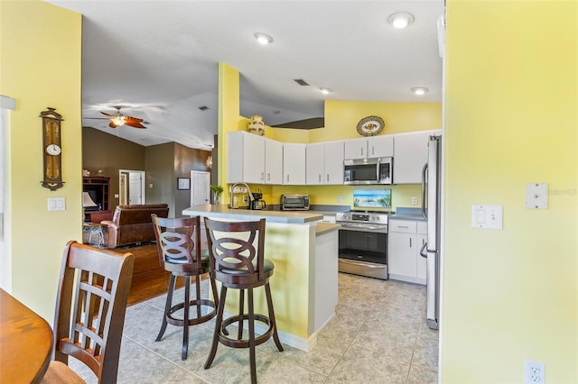 kitchen with stainless steel appliances, white cabinetry, a breakfast bar area, and kitchen peninsula