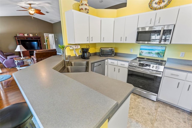 kitchen featuring kitchen peninsula, appliances with stainless steel finishes, white cabinetry, and sink