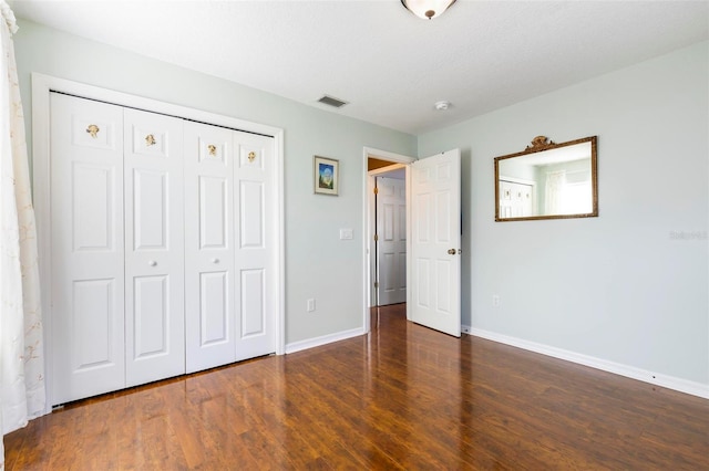 unfurnished bedroom featuring a closet and dark wood-type flooring