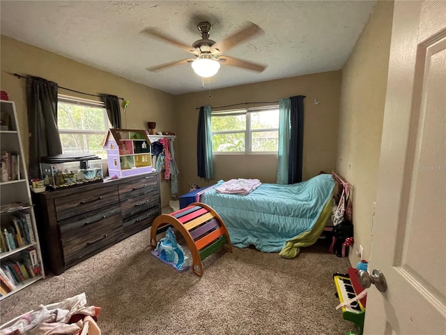 carpeted bedroom with a textured ceiling, multiple windows, and ceiling fan