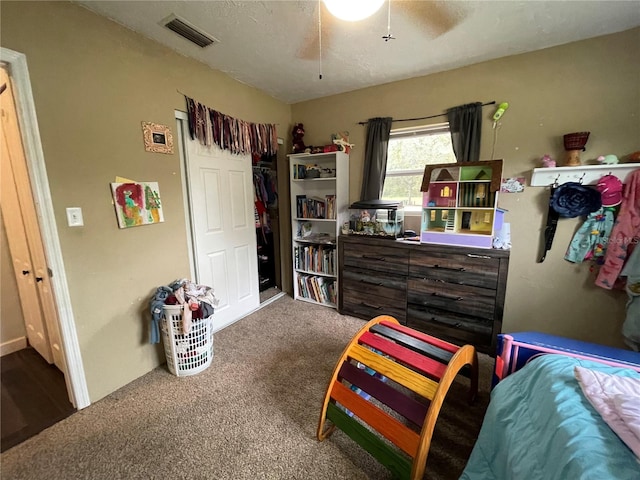 carpeted bedroom featuring ceiling fan and a textured ceiling