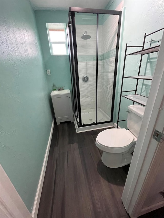 bathroom featuring toilet, hardwood / wood-style floors, and a shower with shower door