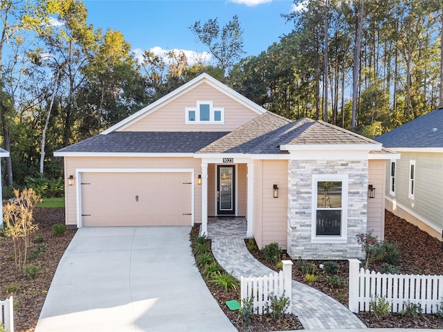 1023 NW 132nd Blvd, Newberry, FL 32669 - view of front of house featuring fence, an attached garage, concrete driveway, a shingled roof, and stone siding