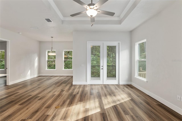 unfurnished living room with ceiling fan, french doors, dark hardwood / wood-style flooring, and a tray ceiling