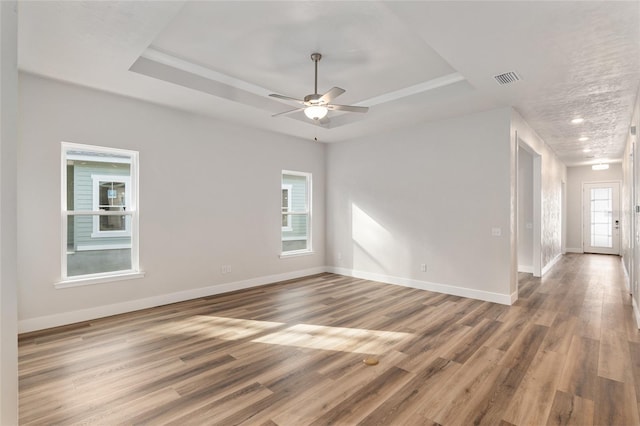 spare room with hardwood / wood-style floors, ceiling fan, and a raised ceiling