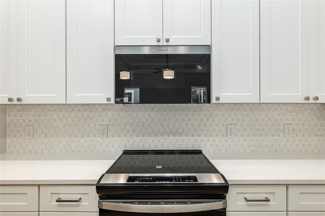 1023 NW 132nd Blvd, Newberry, FL 32669 - kitchen with range with electric stovetop, white cabinetry, decorative backsplash, and light stone countertops
