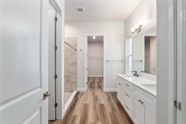 bathroom featuring hardwood / wood-style flooring, vanity, and tiled shower