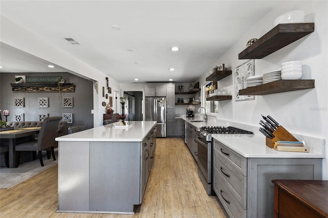 kitchen featuring gray cabinetry, light hardwood / wood-style floors, a kitchen island, and appliances with stainless steel finishes