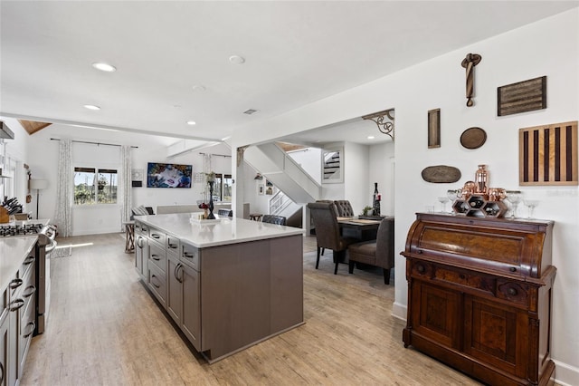 kitchen featuring beamed ceiling, gas stove, light hardwood / wood-style flooring, and a kitchen island