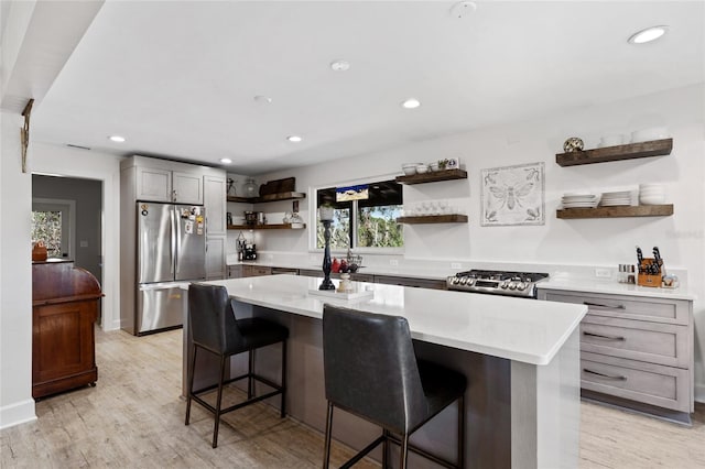 kitchen featuring a kitchen bar, a center island, stainless steel appliances, and light hardwood / wood-style floors