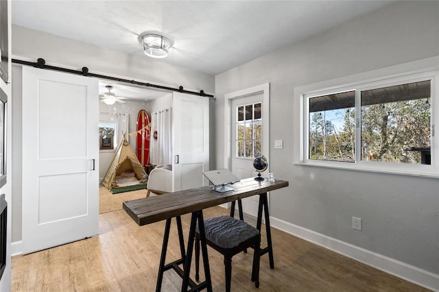 dining room featuring hardwood / wood-style floors, a barn door, and ceiling fan