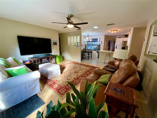 living room featuring ceiling fan with notable chandelier and light wood-type flooring