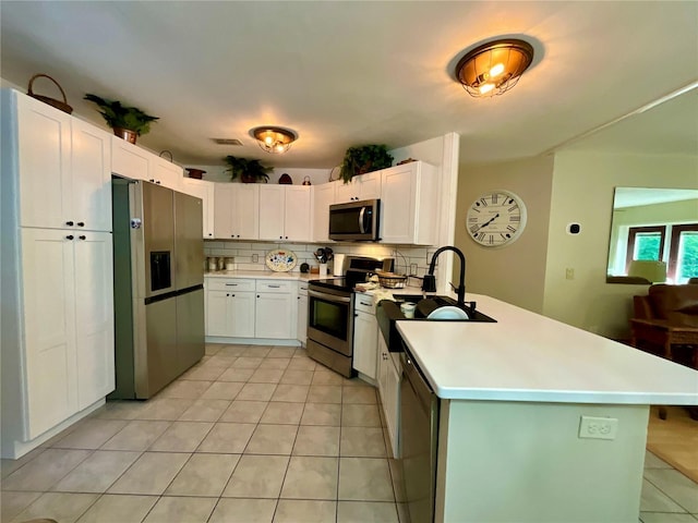 kitchen with appliances with stainless steel finishes, backsplash, sink, white cabinets, and light tile patterned flooring