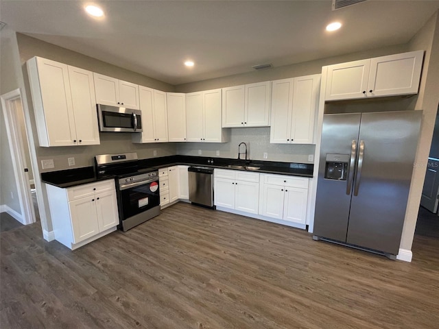 kitchen with white cabinets, appliances with stainless steel finishes, dark wood-type flooring, and sink