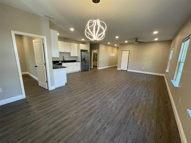 kitchen featuring dark hardwood / wood-style flooring, stainless steel fridge, pendant lighting, white cabinets, and ceiling fan with notable chandelier