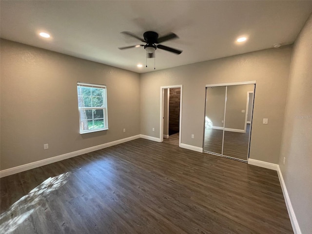 unfurnished bedroom with dark hardwood / wood-style flooring, a closet, and ceiling fan