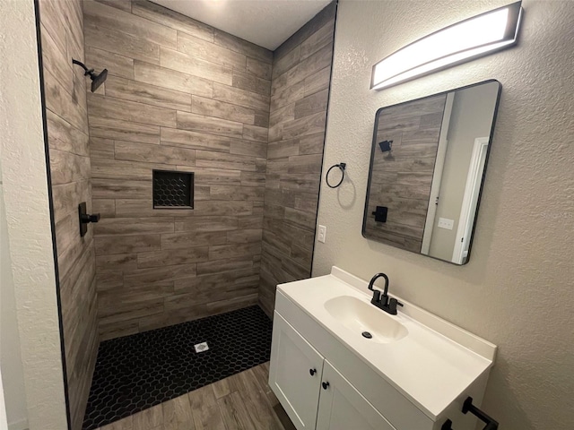 bathroom with a tile shower, hardwood / wood-style floors, and vanity